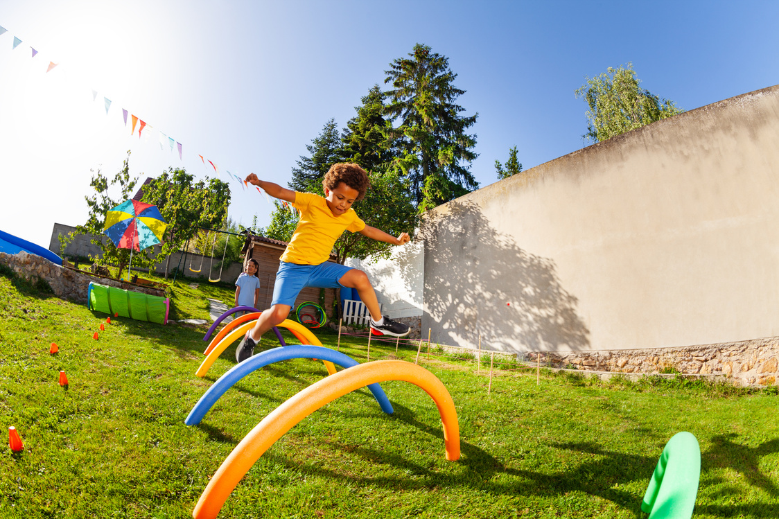 Child running through an obstacle course outdoors at summer camp